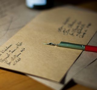 Close-up of vintage letters with a pen and ink, showcasing classic handwriting.